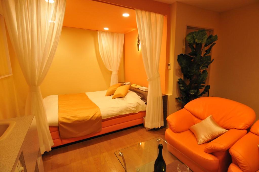 une chambre avec un lit orange et une chaise dans l'établissement Ｈｏｔｅｌkura, à Sodegaura