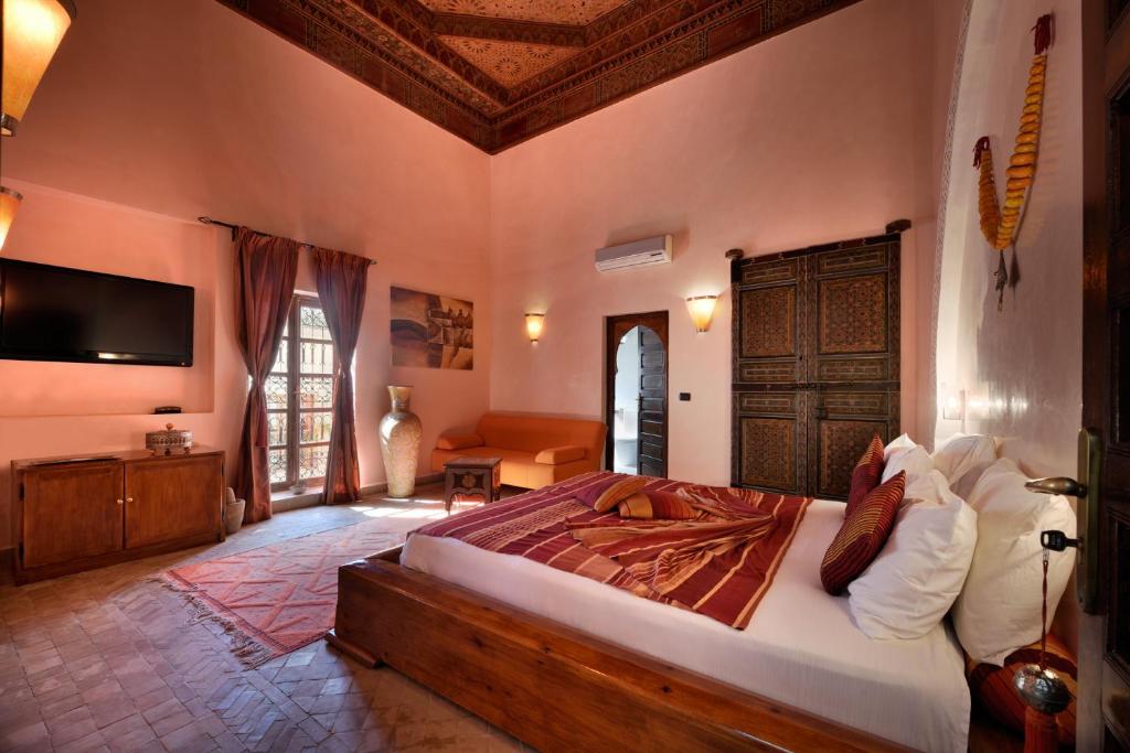 une chambre avec un grand lit et une télévision dans l'établissement Riad les Ammonites and Spa, à Marrakech