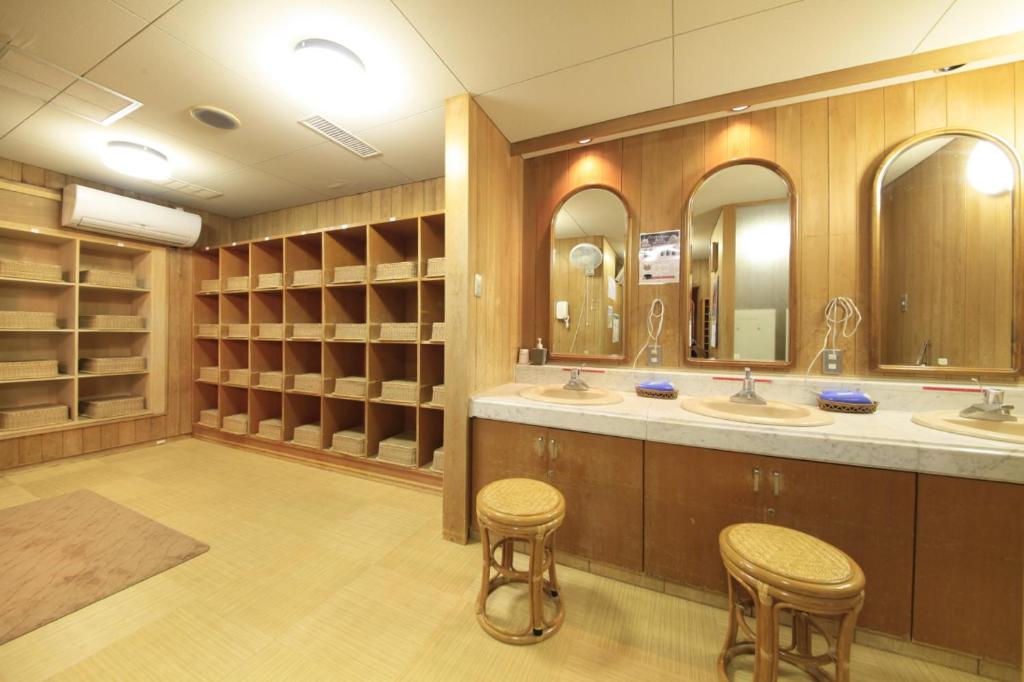 une grande salle de bain avec deux lavabos et deux tabourets dans l'établissement Kasuga no Mori, à Saku