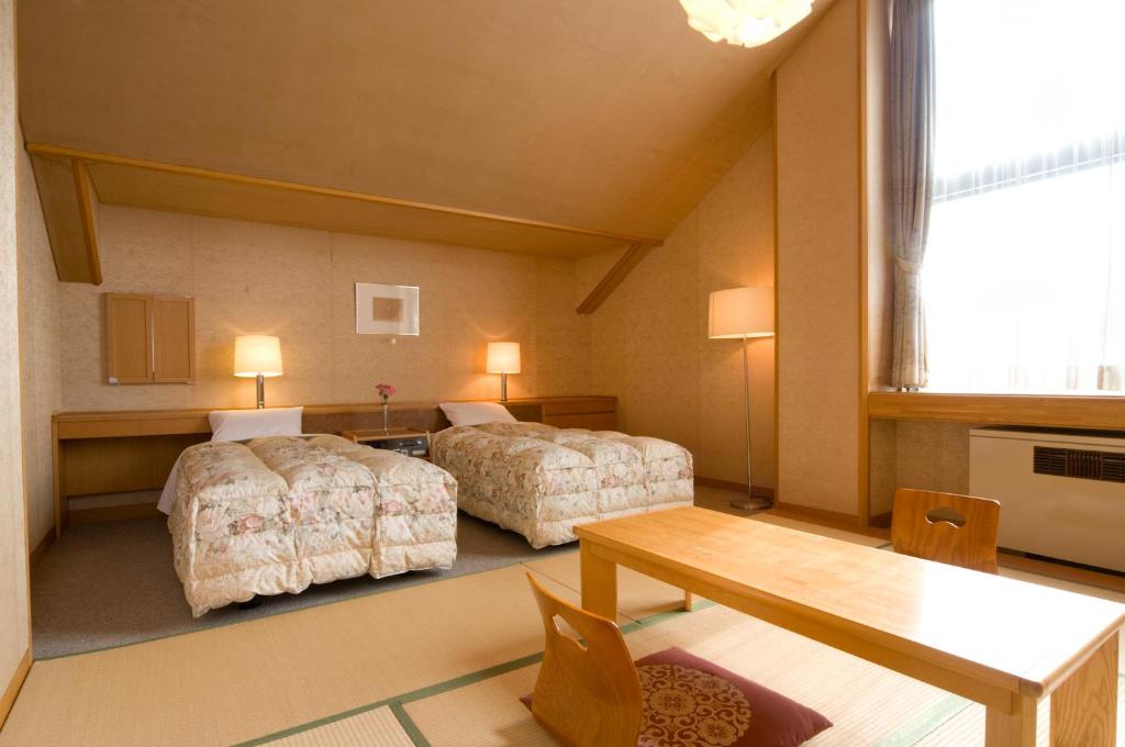 une chambre d'hôtel avec deux lits et une table dans l'établissement Kasuga no Mori, à Saku 18 autres photos