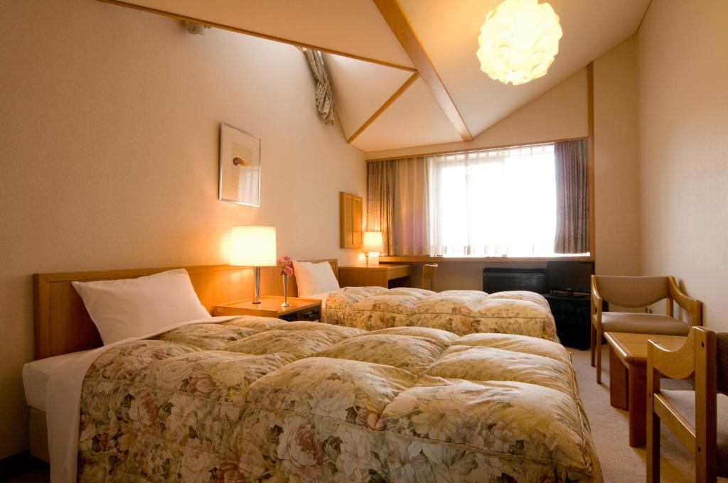 une chambre d'hôtel avec trois lits et une fenêtre dans l'établissement Kasuga no Mori, à Saku