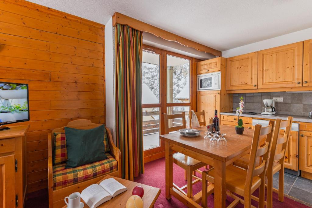 une cuisine et une salle à manger avec une table et des chaises dans l'établissement travelski home select - Résidence Les Chalets du Galibier, à Valloire