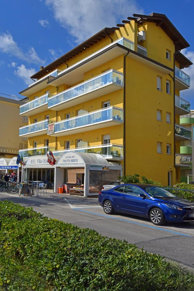 une voiture bleue garée devant un bâtiment jaune dans l'établissement Hotel Villa Olga, à Caorle