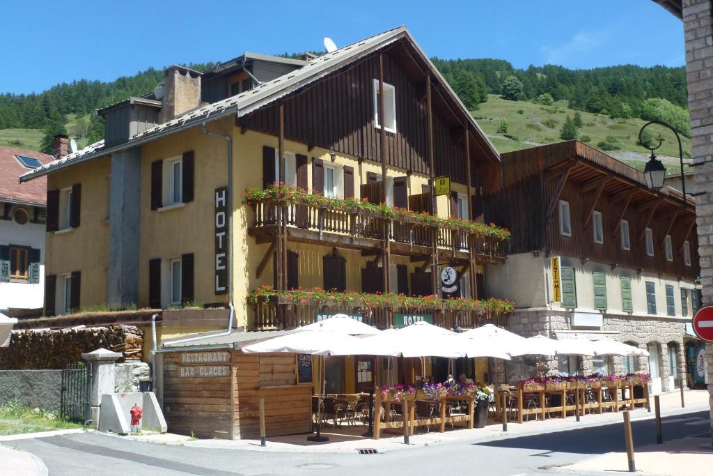 un bâtiment avec des tables et des parasols devant lui dans l'établissement Chalet de Lanza, à Abriès
