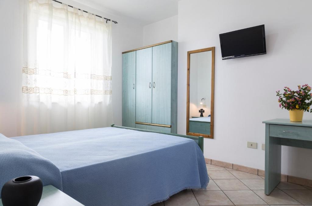 une chambre avec un lit bleu et une télévision dans l'établissement Happy Days, à Capo Vaticano