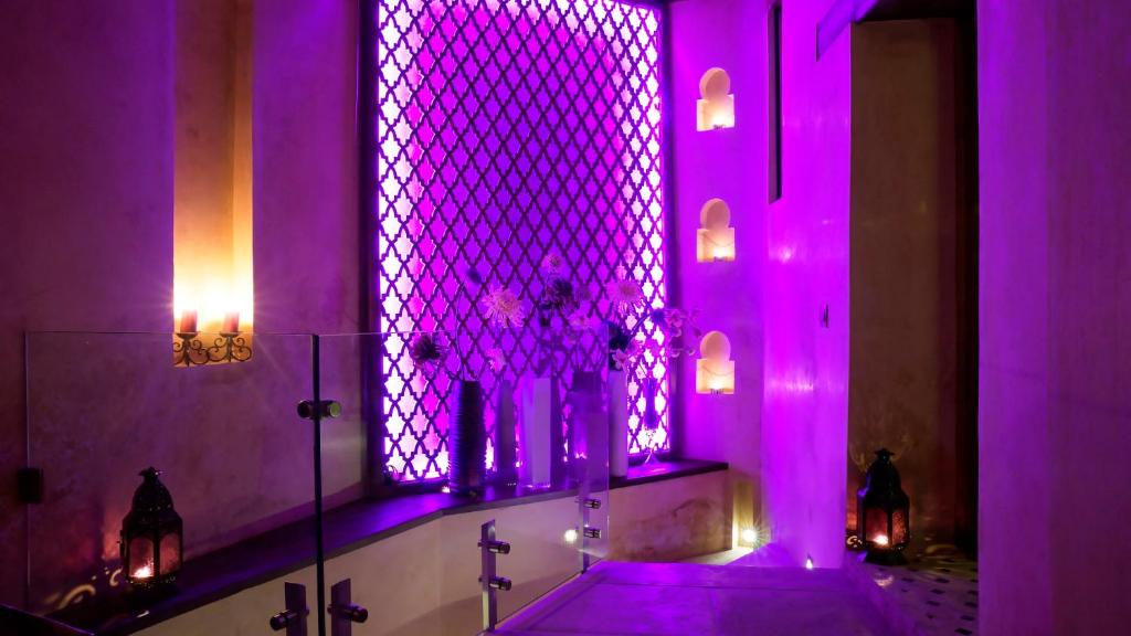 La salle de bains est pourvue d'un éclairage violet et d'une baignoire avec une fenêtre. dans l'établissement Karawan Riad, à Fès 20 autres photos