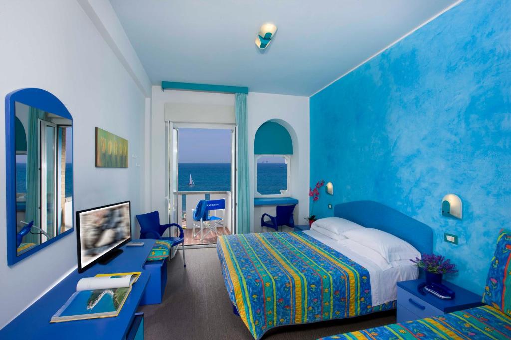 une chambre d'hôtel avec un lit et un mur bleu dans l'établissement Hotel Napoleon, à Pesaro