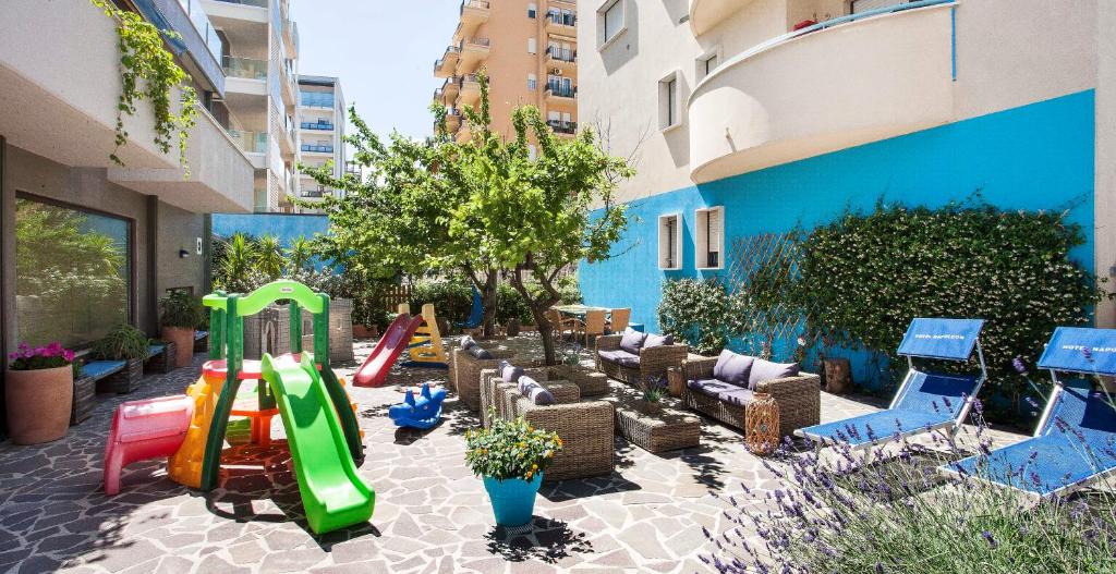 une aire de jeux avec un toboggan, des chaises et une balançoire dans l'établissement Hotel Napoleon, à Pesaro
