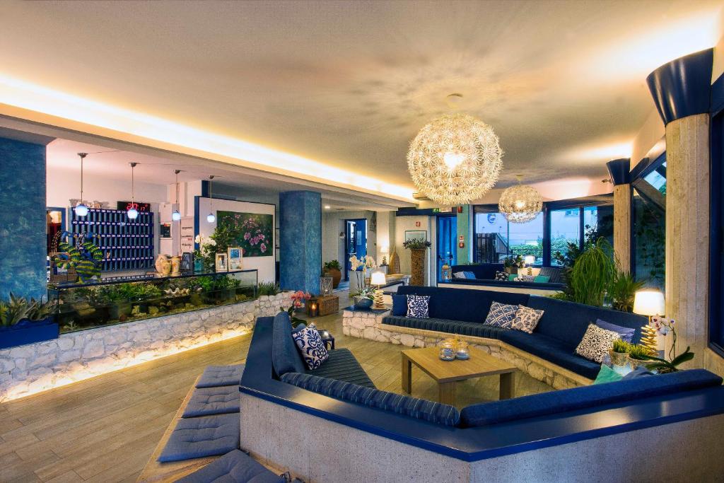 un salon avec des canapés bleus et un lustre dans l'établissement Hotel Napoleon, à Pesaro