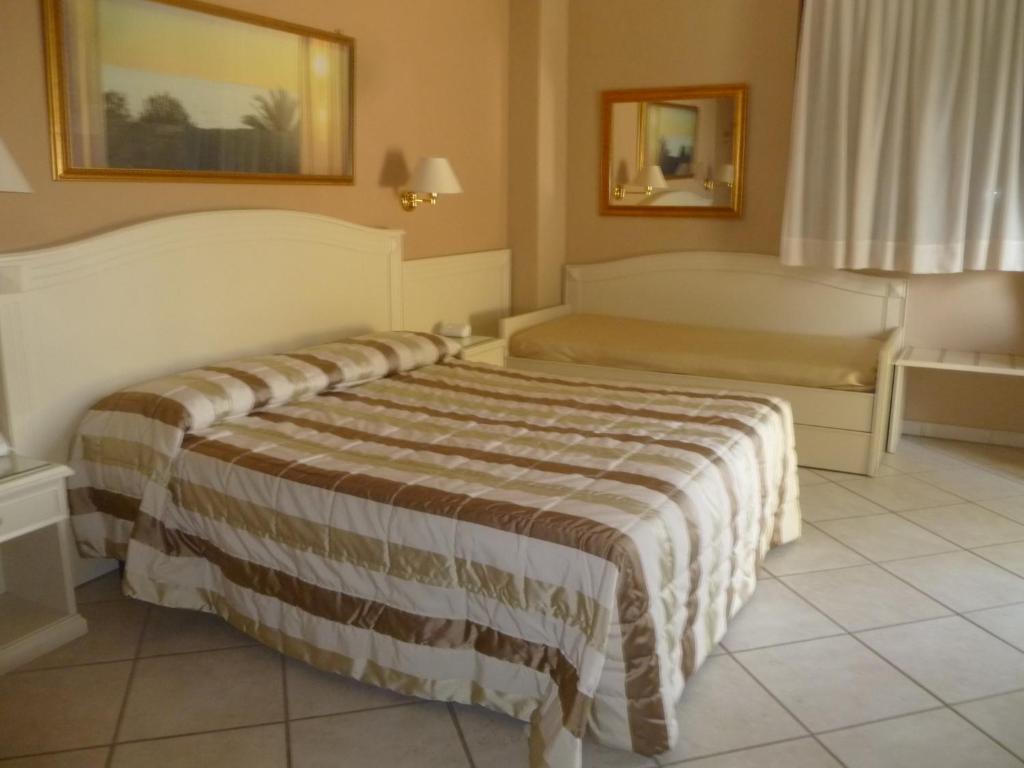 une chambre d'hôtel avec deux lits et un canapé dans l'établissement Conchiglia Azzurra Resort & Beach, à Porto Cesareo 9 autres photos