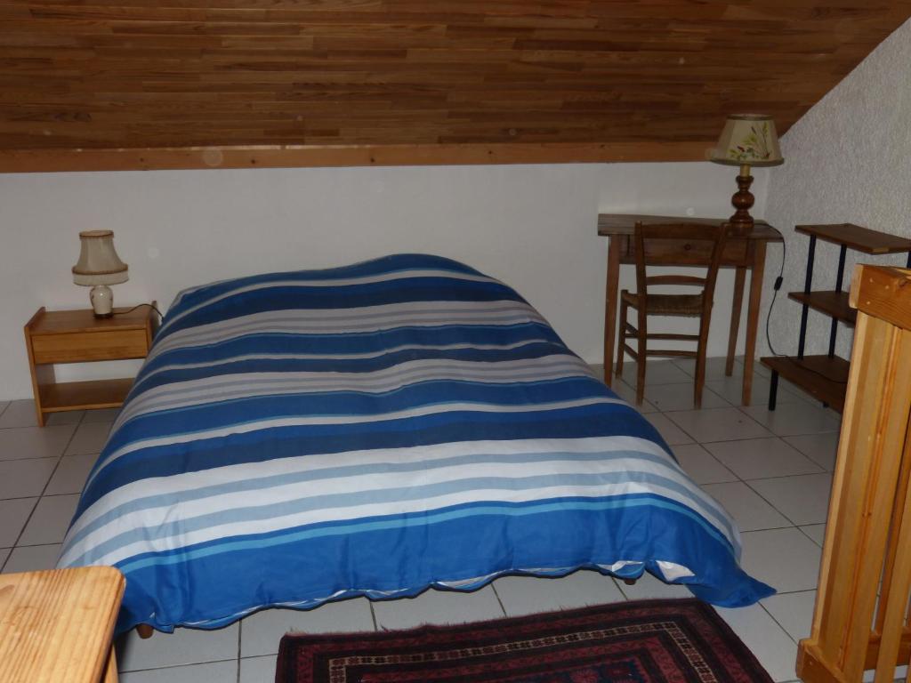 - un lit avec une couverture rayée bleue et blanche dans l'établissement La Balme, à Puy-Saint-Vincent