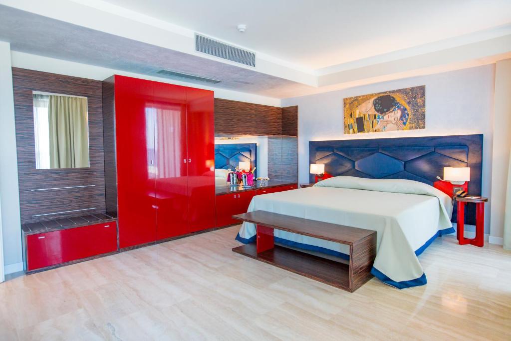 une chambre avec un grand lit et un mur rouge dans l'établissement Victoria Palace Cefalù, à Cefalù 84 autres photos