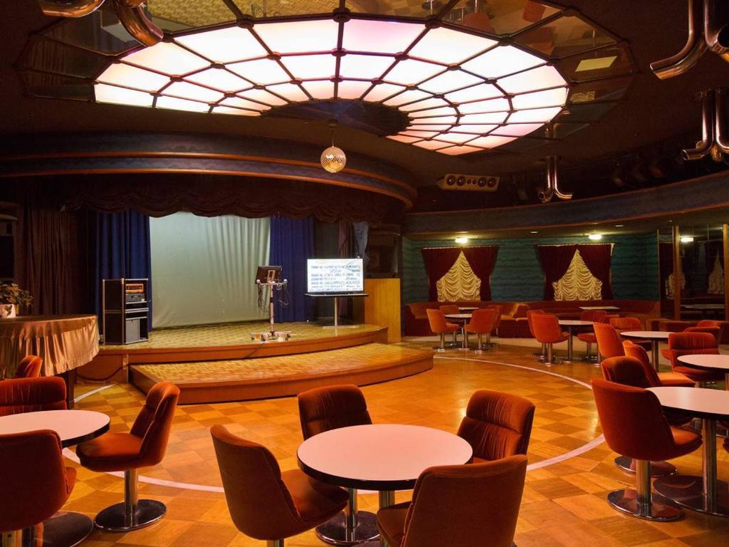 une grande chambre avec des tables, des chaises et une scène dans l'établissement Hotel Oonoya, à Atami 45 autres photos