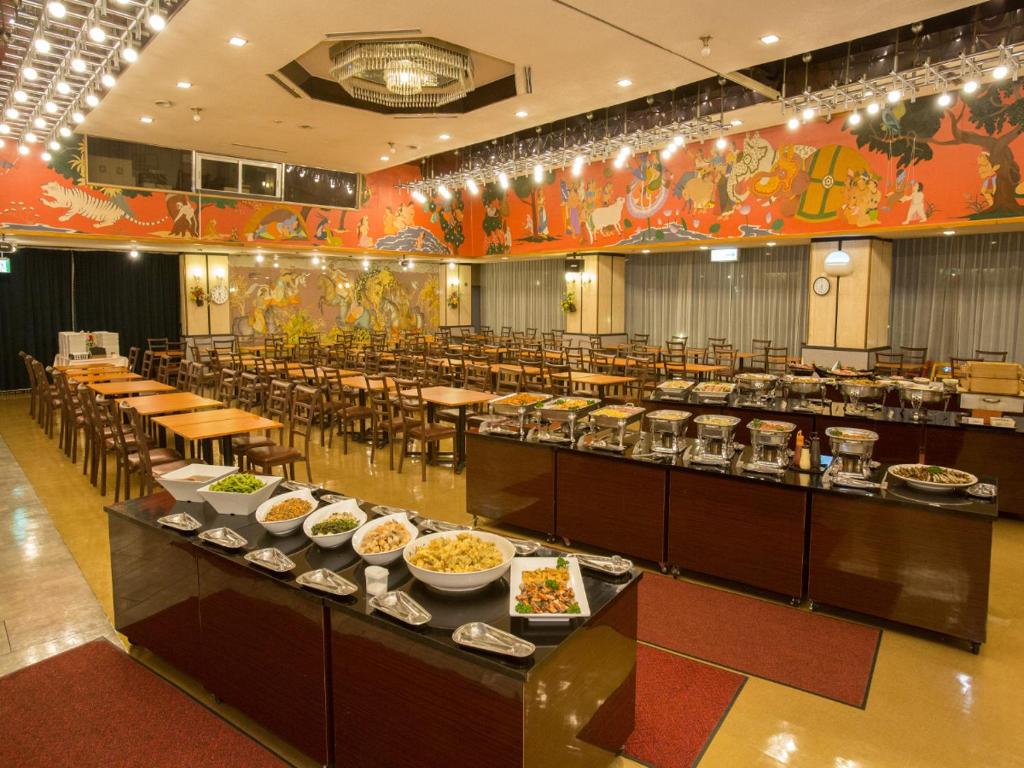 une salle à manger avec des tables et des bols de nourriture dans l'établissement Ikaho Grand Hotel, à Shibukawa