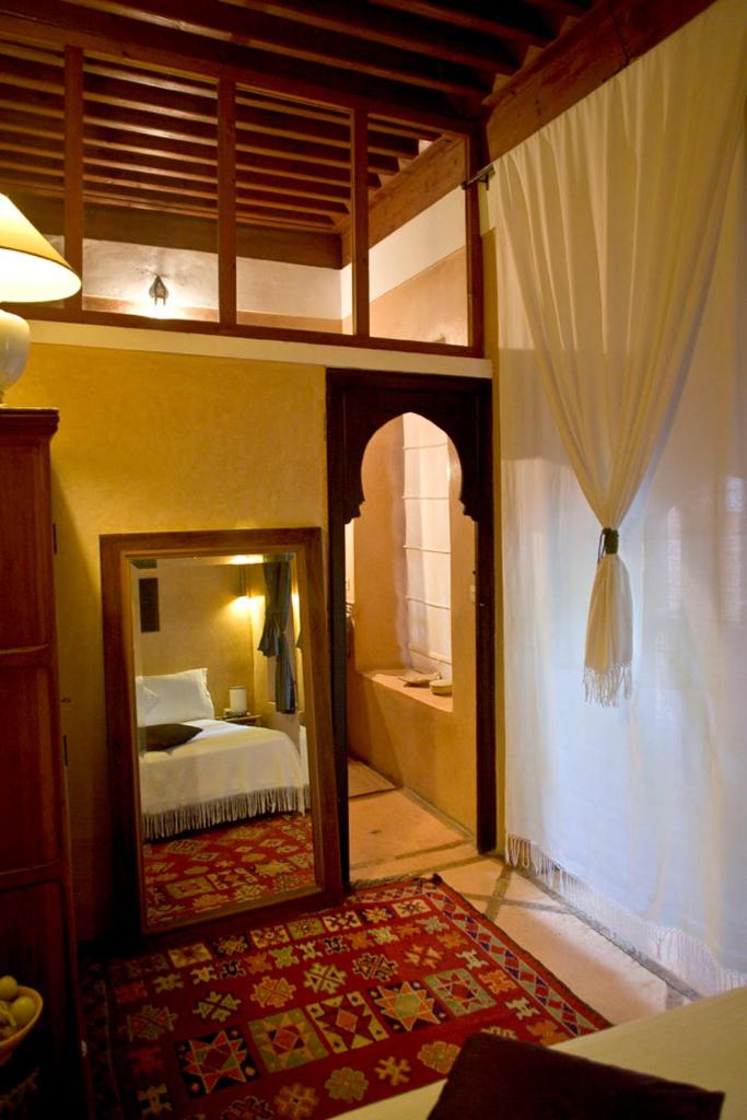 - une chambre avec un miroir, un lit et un lit dans l'établissement Dar Attajmil, à Marrakech