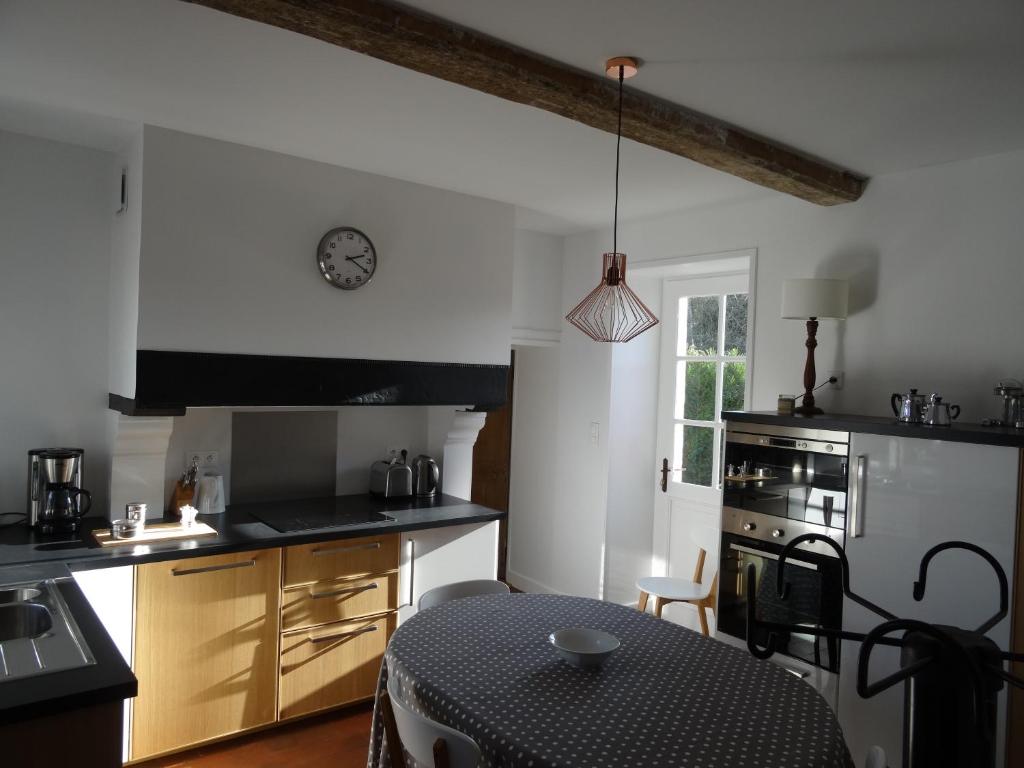 une cuisine avec une table et une horloge au mur dans l'établissement Gite de l'Abbaye d'Etrun, à Étrun