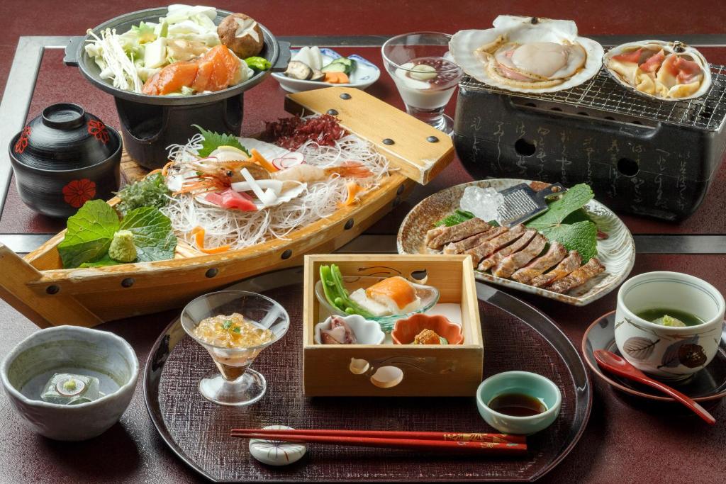 une table avec des assiettes et des bols de nourriture dans l'établissement Takinoya Bekkan Tamanoyu, à Noboribetsu