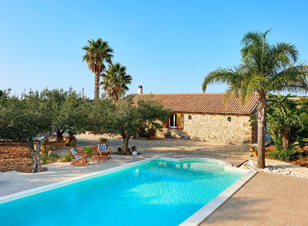 une piscine devant une maison avec des palmiers dans l'établissement Villa Le Sterlizie, à Castellammare del Golfo