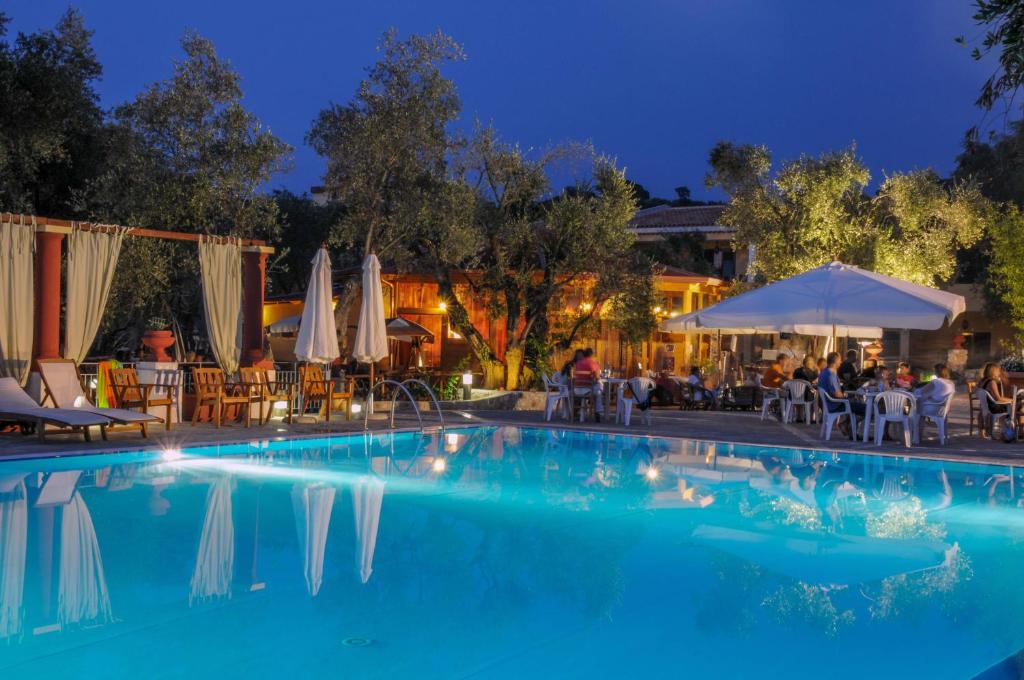 une piscine la nuit avec tables et parasols dans l'établissement Hotel Resort Poggio degli Ulivi, à Rodi Garganico