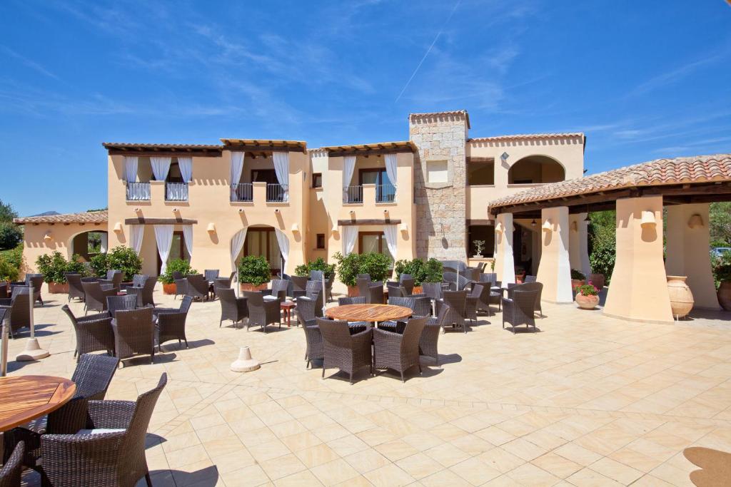 une terrasse avec des tables et des chaises devant un bâtiment dans l'établissement Hotel Baia Del Porto, à Budoni