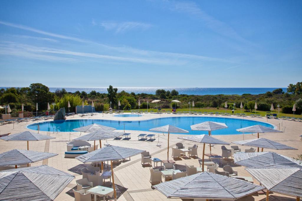 une piscine avec parasols et chaises et une piscine dans l'établissement Hotel Baia Del Porto, à Budoni