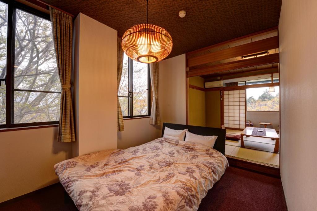 une chambre avec un lit dans une pièce avec des fenêtres dans l'établissement Mizu no Kaori, à Hakone