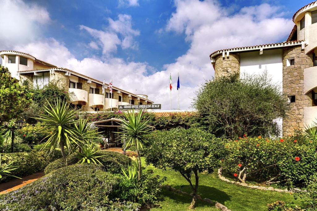 une vue de la façade d'un hôtel avec des plantes dans l'établissement Grand Hotel Smeraldo Beach, à Baja Sardinia