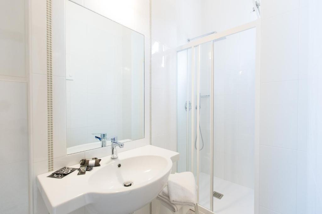 une salle de bain blanche avec lavabo et douche dans l'établissement Hotel Confort, à Cattolica