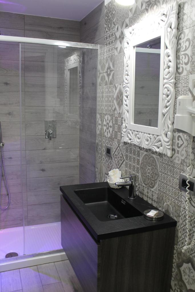 une salle de bain avec un lavabo et une douche avec un miroir dans l'établissement Hotel Miramare, à Cirò Marina