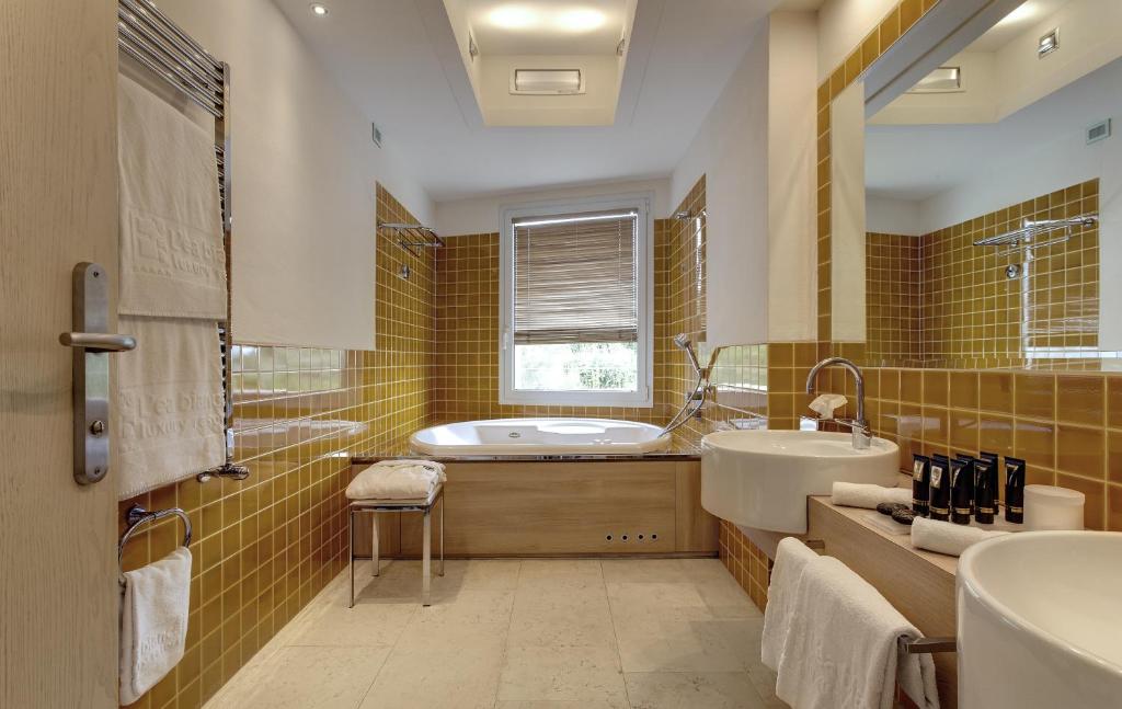 une salle de bains avec baignoire et lavabo dans l'établissement L'Ea Bianca Luxury Resort, à Baja Sardinia