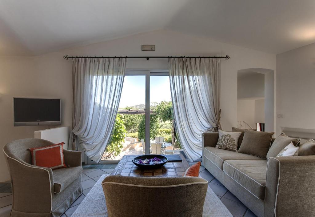 un salon avec un canapé et des chaises et une grande fenêtre dans l'établissement L'Ea Bianca Luxury Resort, à Baja Sardinia