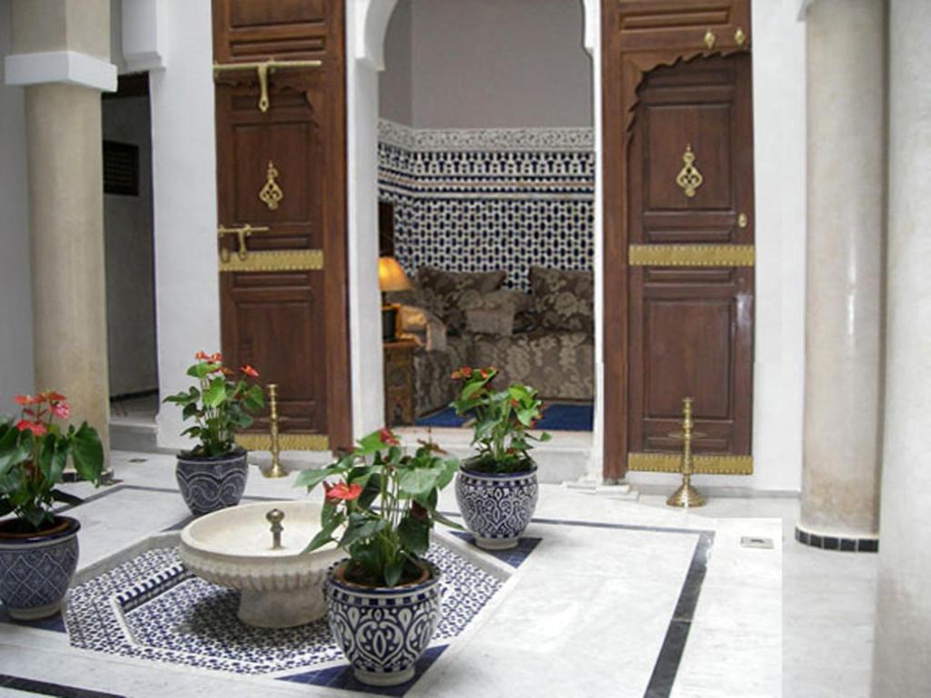 un hall avec une fontaine et des plantes en pot dans un bâtiment dans l'établissement Dar Eva, à Fès