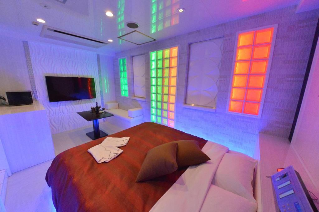 - une chambre avec un grand lit et des lumières colorées dans l'établissement Terrace M Yokota Bace ( Adult Only ), à Hakonegasaki
