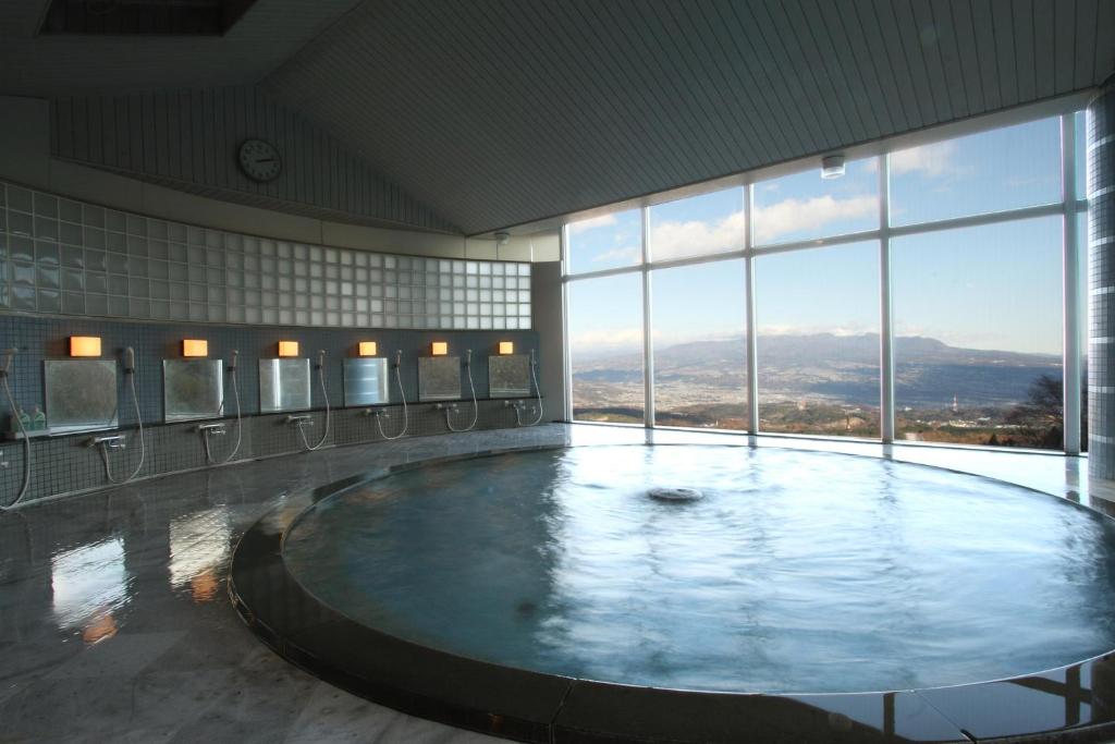 une grande piscine d'eau dans une salle de bain avec des fenêtres dans l'établissement Shinki, à Shibukawa