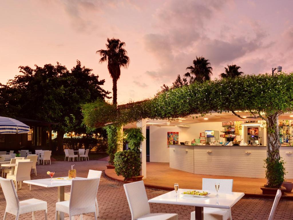 un restaurant avec des tables blanches et des chaises blanches dans l'établissement TH Simeri - Simeri Village, à Simeri Mare