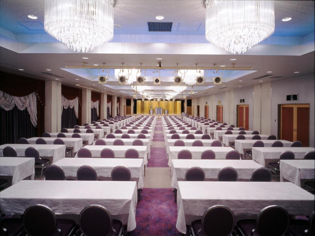 Cette chambre comprend des tables et des chaises blanches ainsi que des lustres. dans l'établissement Hotel Ravie Kawaryo, à Itō 35 autres photos