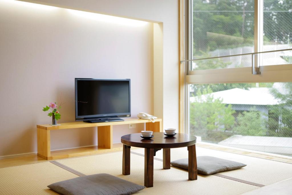 un salon avec une télévision et une table basse dans l'établissement Kusatsu Hotel Bekkan Wata no Yu (Adult Only), à Kusatsu