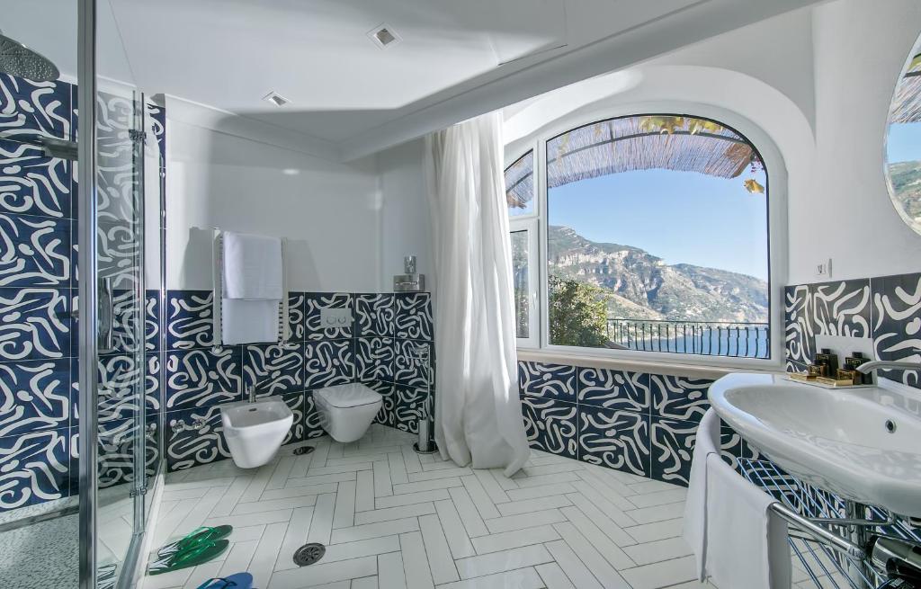 une salle de bain avec une baignoire, un lavabo et une fenêtre dans l'établissement Hotel Le Agavi, à Positano