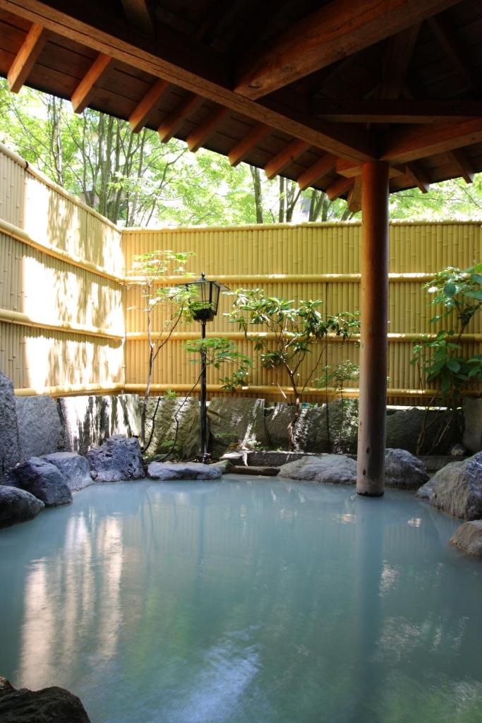 une grande piscine d'eau sous une clôture en bois dans l'établissement Oyado Kiyomizuya, à Noboribetsu