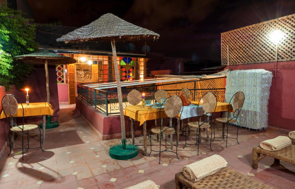 un restaurant avec une table, des chaises et un parasol dans l'établissement Riad Dar Jdati, à Marrakech