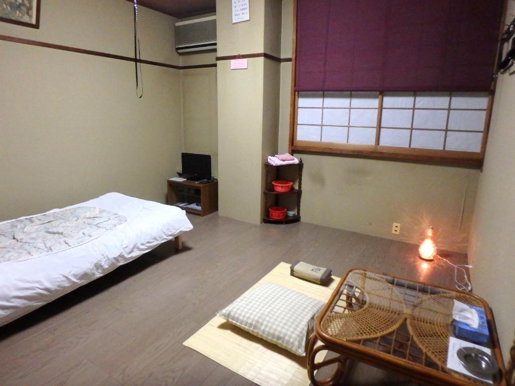 une pièce avec un lit et une table dedans dans l'établissement Azuma no Yu, à Nagano