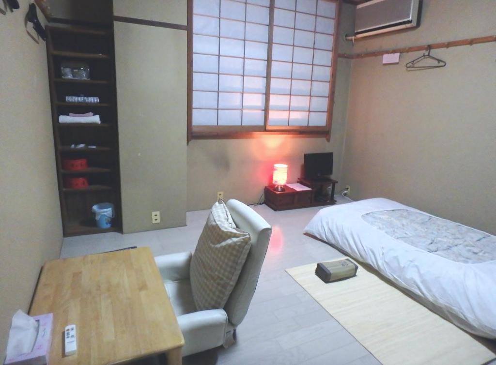 une chambre avec un lit, une chaise et une table dans l'établissement Azuma no Yu, à Nagano