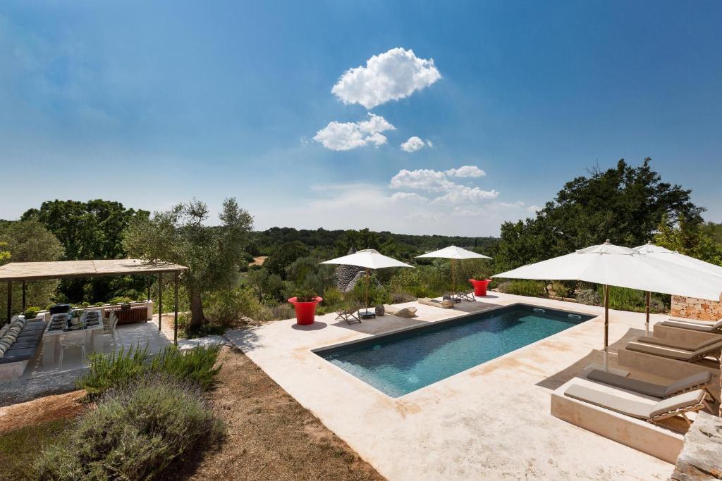 une piscine avec chaises et parasols dans une cour dans l'établissement La Gastalena by BarbarHouse, à Ostuni