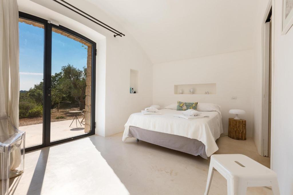 une chambre blanche avec un lit et une grande fenêtre dans l'établissement La Gastalena by BarbarHouse, à Ostuni