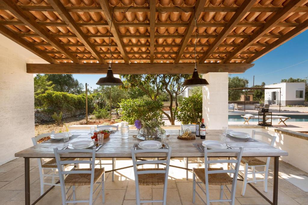 une table et des chaises en bois sous une pergola en bois dans l'établissement Le Cerase, à Salve