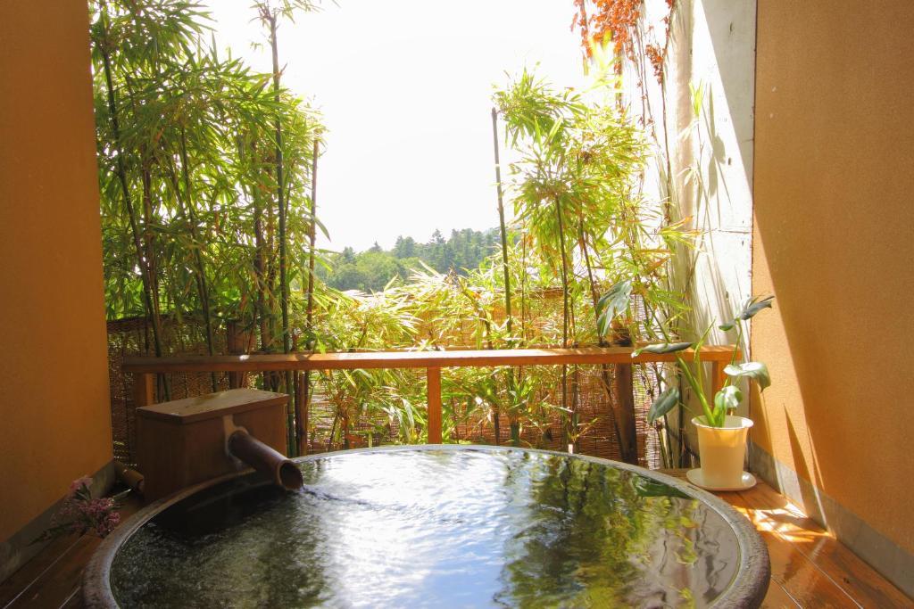 d'un bain à remous sur un balcon avec vue sur les arbres. dans l'établissement Nasubi no Hana, à Itō
