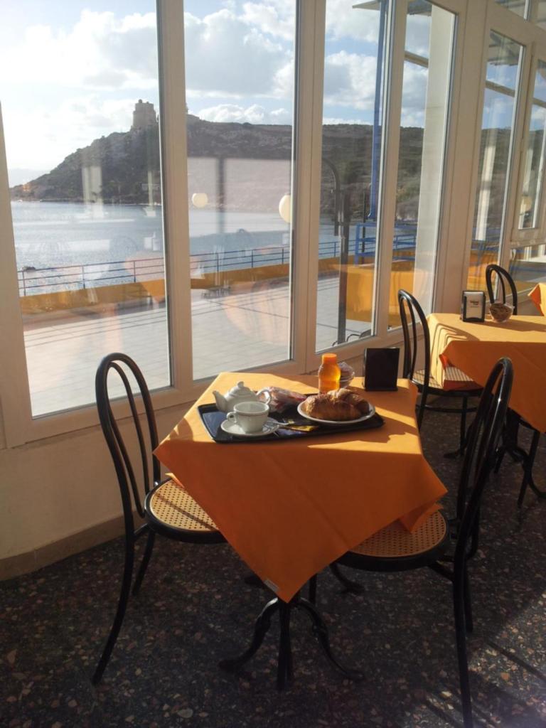 une table et des chaises avec une assiette de nourriture dans l'établissement Hotel Calamosca, à Cagliari