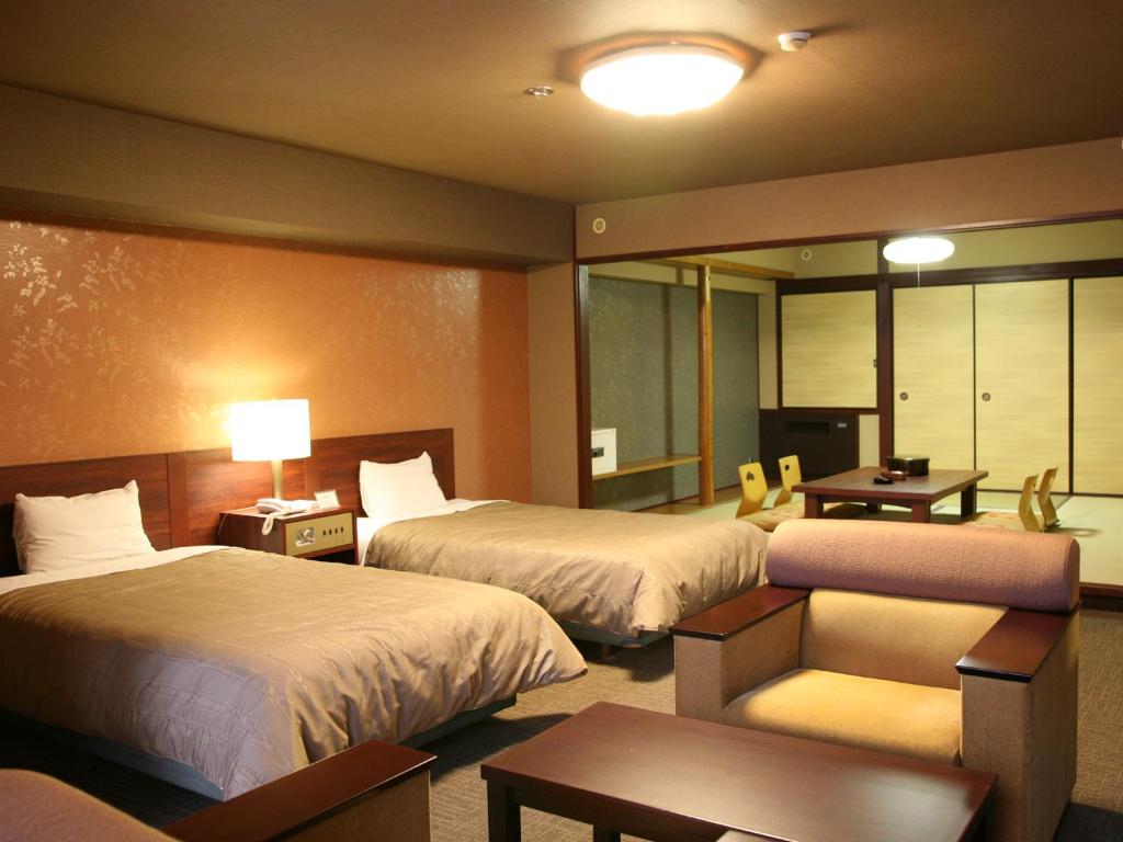une chambre d'hôtel avec deux lits et un bureau dans l'établissement Hotel Kirishima Castle, à Kirishima
