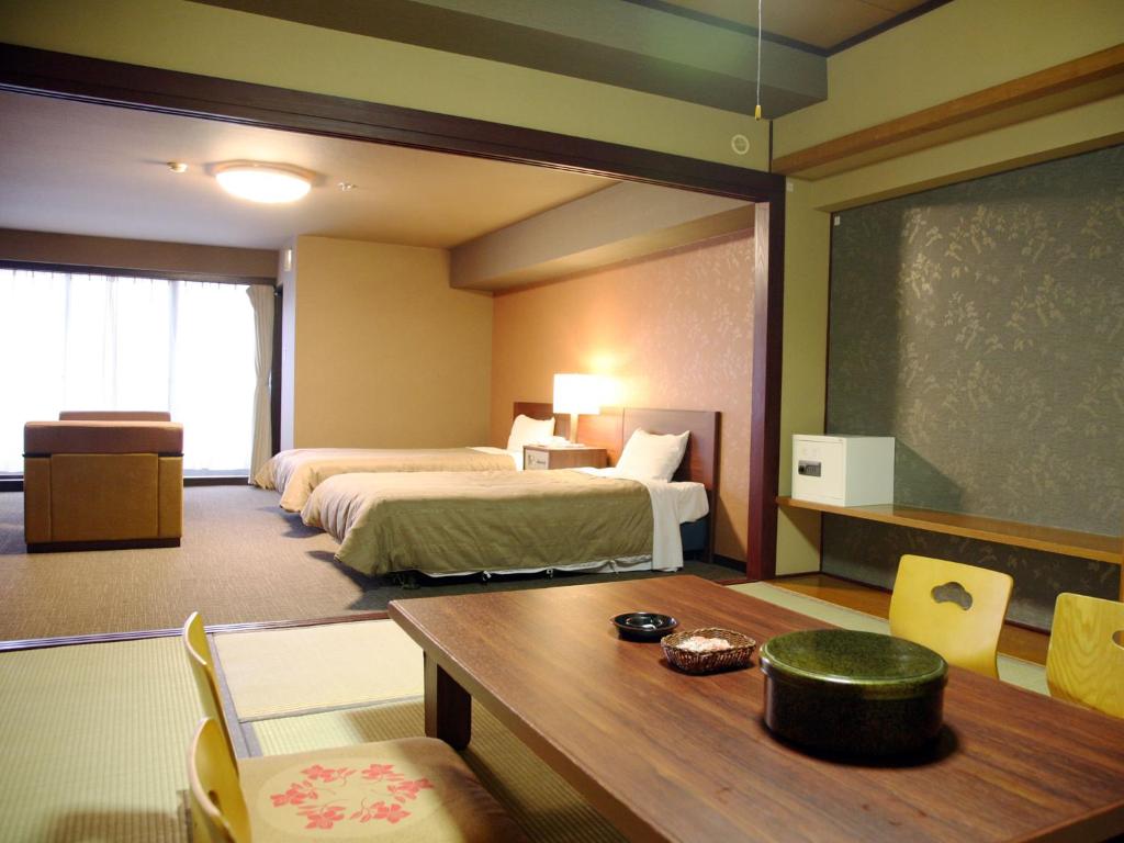 Cette chambre comprend 2 lits, une table et un tableau noir. dans l'établissement Hotel Kirishima Castle, à Kirishima