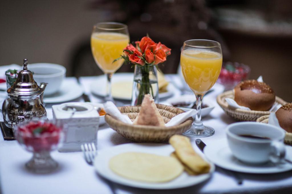 une table avec des assiettes de nourriture et des verres de jus d'orange dans l'établissement Riad Dar More, à Marrakech